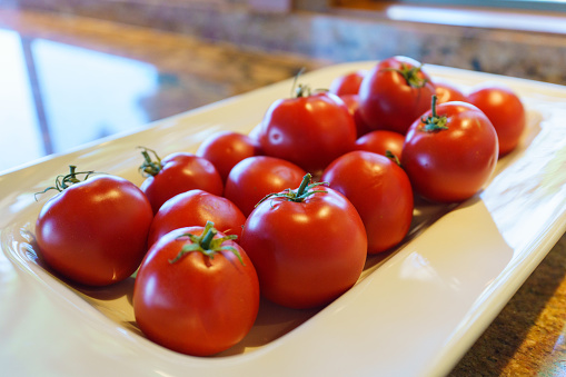 Tomatoes on a plate on the counter in a kitchen