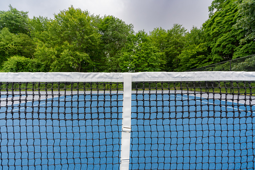 Example of a new blue tennis court with white lines and gray out of bounds that could be found at a park or recreation facility.