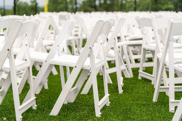 istock White chairs set-up in rows on a green synthetic turf athletic field for a high school graduation ceremony. 1421742375