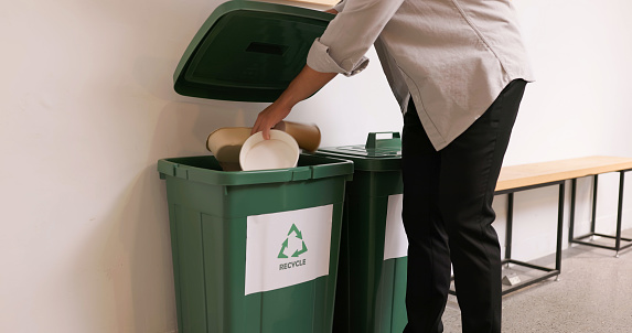 Waste separation and environmental friendly in business office - close up of Man throwing paper container into recycling bin