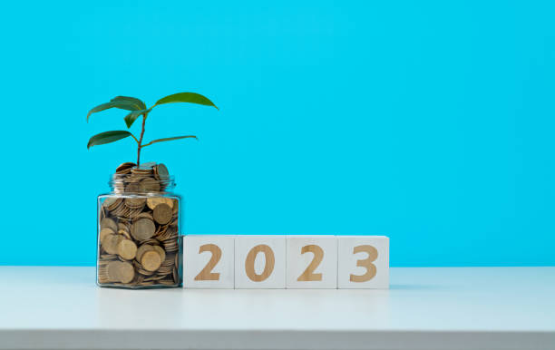 istock Coin jar and number 2023 on white table 1421752201