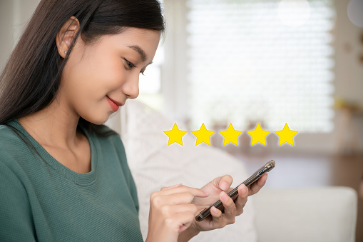 Customer service experience and business satisfaction survey. Woman hand using smart phone with icon five star symbol to increase rating of company concept