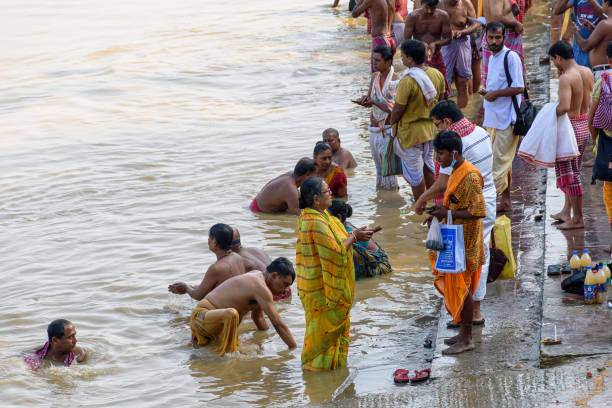 Indian Hindu people do Faithful offer Tarpan to the divine for the liberation of the soul of their deceased elders at Mahalaya Paksha and Sola Shraddha. Kolkata, West Bengal, India on October 2021. stock photo
