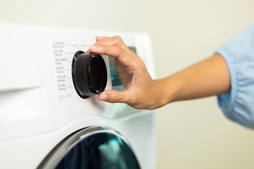 Finger of woman press the switch to make the washing machine work. Home appliances.