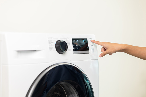 Finger of woman press the switch to make the washing machine work. Home appliances.