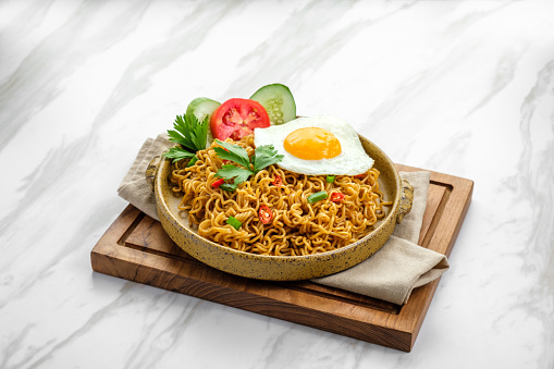 Fried noodle served on marble background with a fresh sunny side up egg