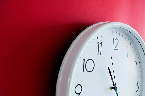 White wall clock on red background.