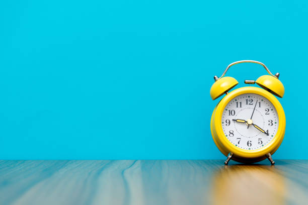 Yellow alarm clock on the wooden table.