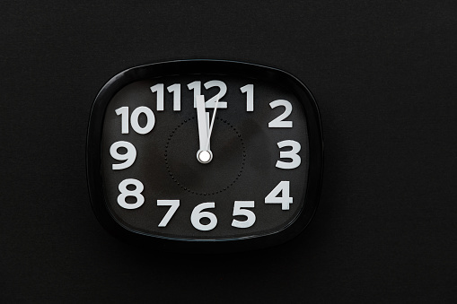 Modern alarm clock on black background.