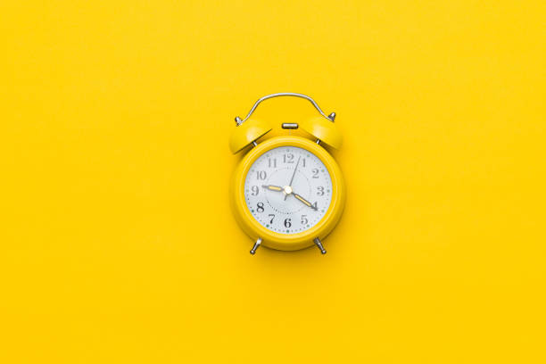 istock Yellow alarm clock on yellow background 1421762381