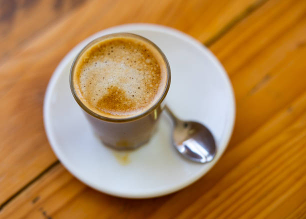 americano cup on saucer with spoon, ashtray, glass of water on red wooden coffee shop table (espresso, milk, macchiato) european style (cappuccino)