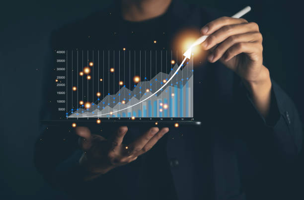 businessman using a laptop to plan a strategy that shows a positive digital technology graph chart. the concept is growing stocks, investing, stock marketing, and success. on a dark background - growth plan graph digital tablet imagens e fotografias de stock