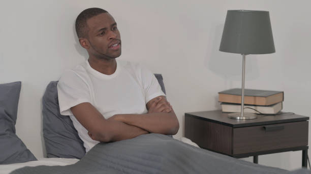 istock Young African Man Sitting in Bed 1421771484