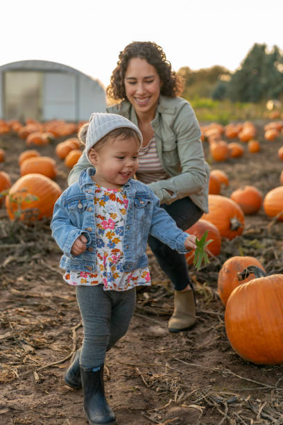 istock Ethnic thirty year old mom playing with her toddler at a pumpkin patch 1421771672