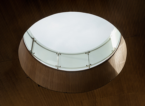 Looking up to the white sky through modern channel round circular ceiling. The sun's rays break through the wooden ceiling, Interior design concept, Space for text, Selective Focus.
