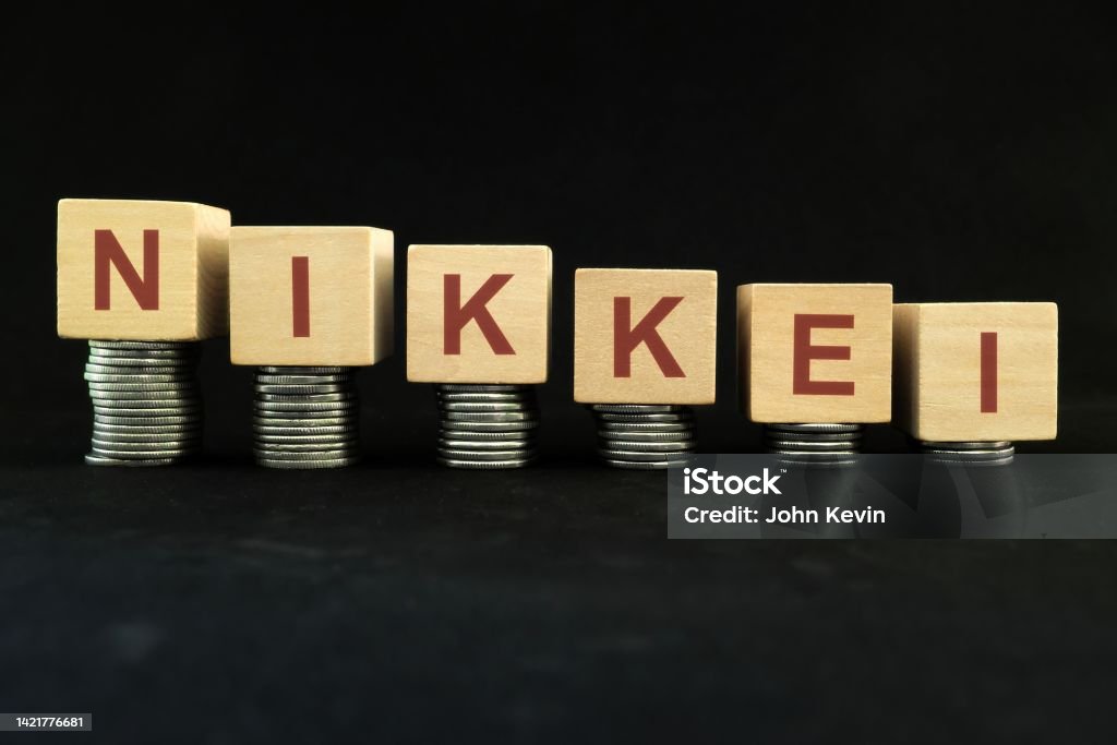 Japanese NIKKEI stock market index crash and bear market due to financial crisis and recession in Japan. Wooden blocks in with coins in dark black background. Arrow Symbol Stock Photo