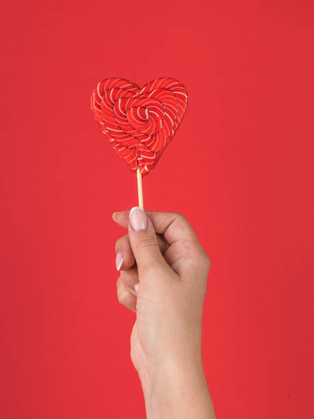 istock A hand with a red heart-shaped candy on a red background. 1421777382