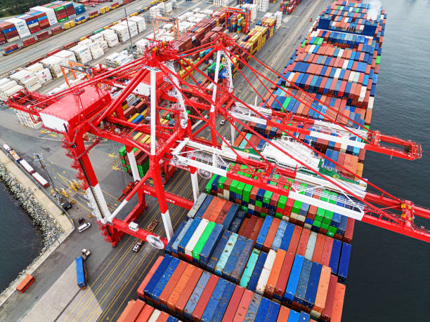 Container Ship at Port Aerial drone view of an enormous (300m) container ship at docked at port. gantry crane stock pictures, royalty-free photos & images