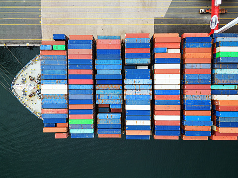 Aerial drone view of an enormous (300m) container ship at docked at port.