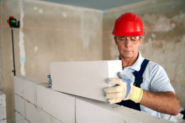 maurer oder maurer legt ziegel, um eine wand aus autoklavierten porenbetonblöcken zu bauen. maurer, der präzises mauerwerk aus schaumbeton mit spirituosen- und laserwaagen durchführt. - mason brick bricklayer installing stock-fotos und bilder