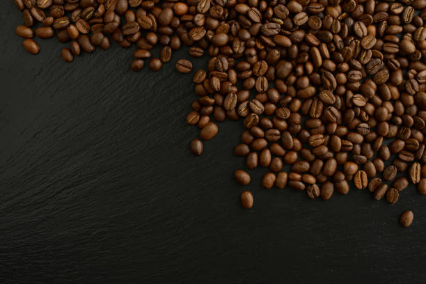 istock Roasted coffee beans on a black background. Beautiful coffee background. Coffee beans on a black stone table 1421781915