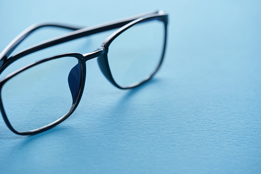 Stylish blue glasses on a blur background.