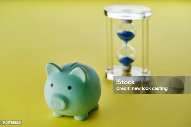Piggy Bank And Hour Glass On Yellow Background Stock Photo - Download Image Now - Urgency, Deadline, Paying