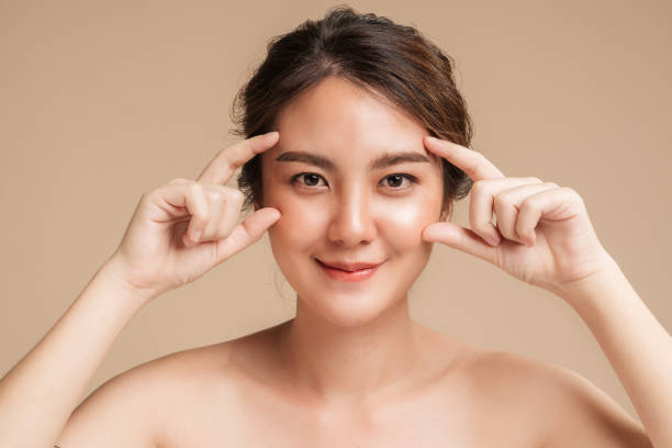 Closeup beautiful Asian woman healthy glowing hydrated skin on beige background. stock photo