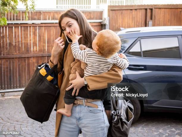 Woman Carrying Her Son Talking On Mobile Phone In Driveway Stock Photo - Download Image Now