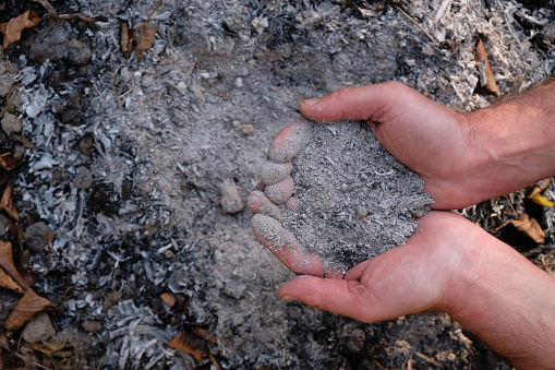 Ashes in men's palms on an ash place background.
