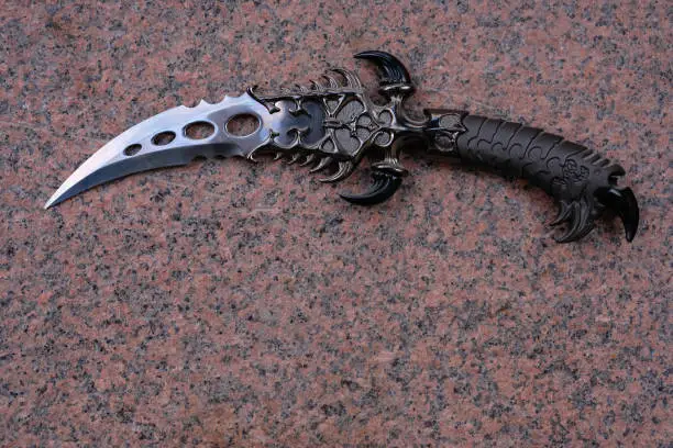 Curved decorative dagger knife on a granite background. Copy space.