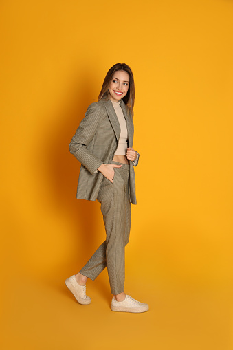 Retrato de cuerpo entero de una hermosa joven con traje de moda sobre fondo amarillo. Vestimenta de negocios photo