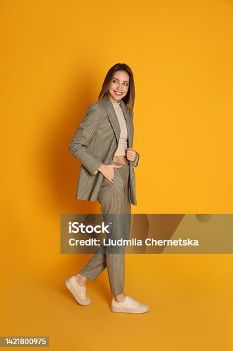 istock Full length portrait of beautiful young woman in fashionable suit on yellow background. Business attire 1421800975