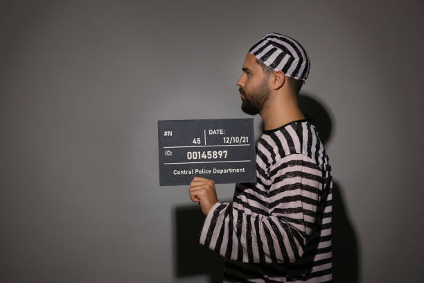 istock Prisoner in special uniform with mugshot letter board 1421801033