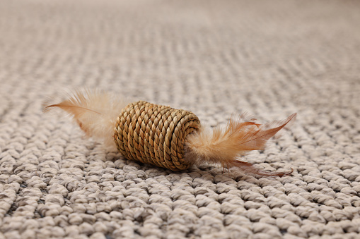 Straw kitten toy with feathers on carpet
