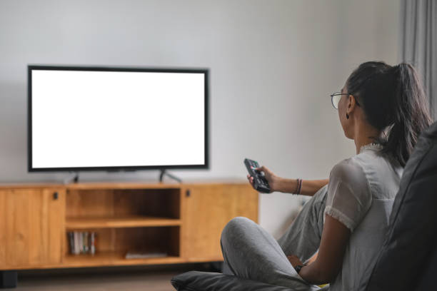 istock Mid Adult Indonesian Woman Changing Channels With Remote Control While Watching TV 1421808190