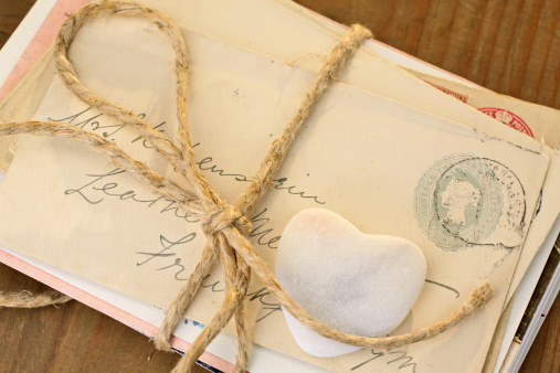 Stone heart with old tied letters on wooden desk
