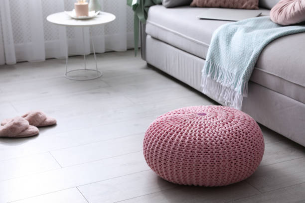 istock Pink knitted pouf near sofa in living room. Space for text 1421812751