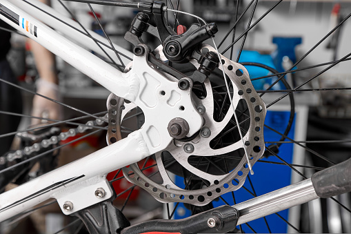 Repair of the brake disc and brake system of a mountain bike in a service workshop. Preventive maintenance and repair of bicycle parts and assemblies in the service