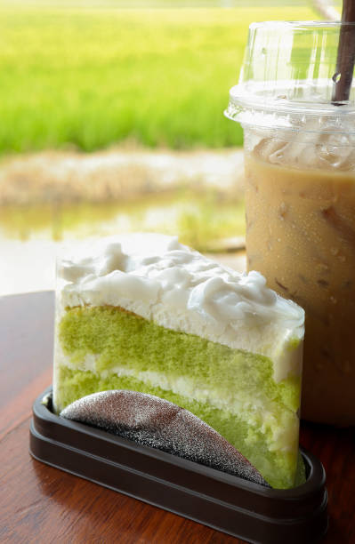 Delicious green chiffon cake or coconut pandan cake with iced coffee on the table. coffee and dessert on the background of the rice field.