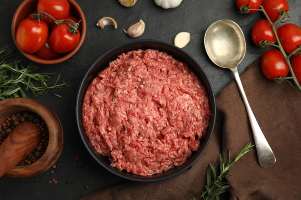 istock Fresh minced meat in bowl and other ingredients on black table, flat lay 1421818433