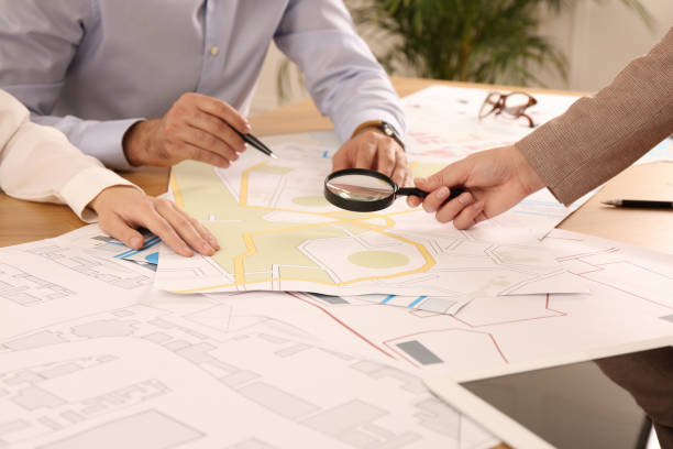 istock Professional cartographers working with cadastral map at table in office, closeup 1421820720