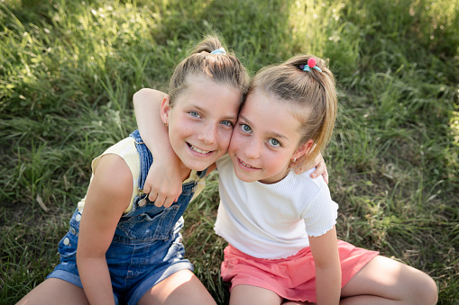 two pretty young girls sisters friends have fun outside in a meadow in summer and are happy