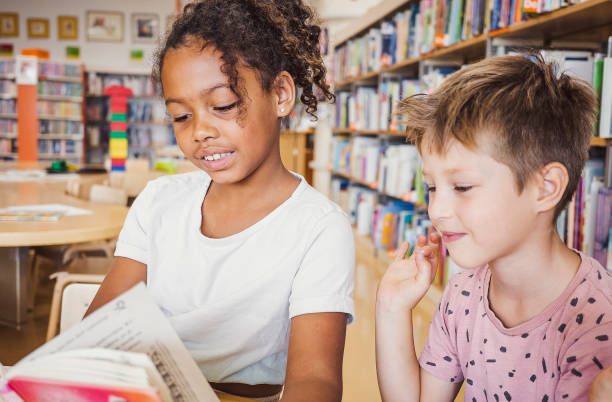 istock Young kids reading a book in the library 1421824431
