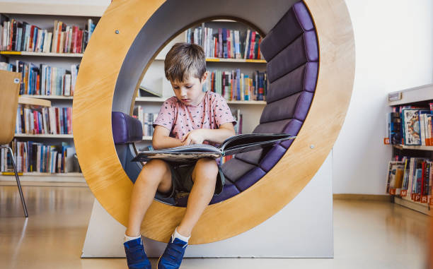 Young kid reading a book in the library stock photo