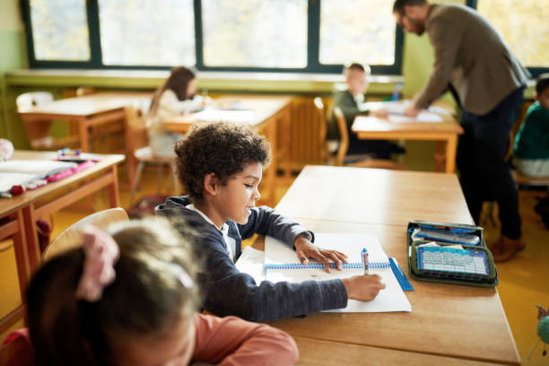 istock Black schoolboy and his friends on a class at elementary school. 1421825896