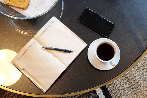 Smartphone and notepad with pen placed on table