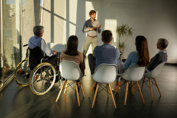 istock Happy male coach talking on a group therapy in the office. 1421828406