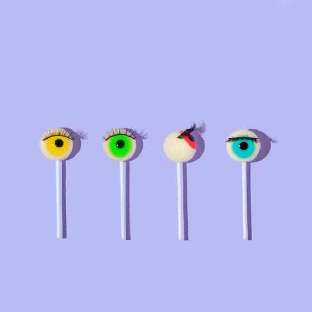 istock Creative layout made with eyeball lollipops with eyelashes  on pastel purple background. Halloween minimal creative concept. Rainbow colored eyes. Modern fashion aesthetic or cosmetic idea. 1421829858