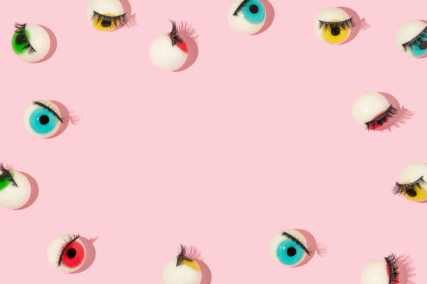 istock Creative pattern or frame made with eyeball figurines with eyelashes on pastel pink background. Halloween minimal creative concept. Rainbow colored eyes. Modern fashion aesthetic idea. 1421829873